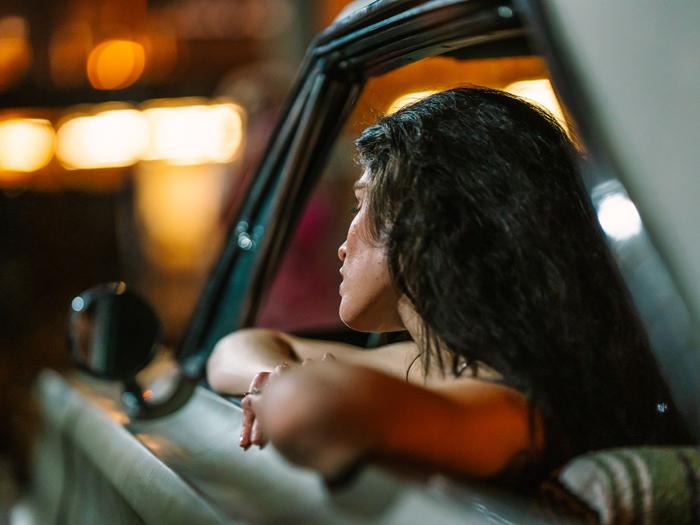 A woman looks out of a car window at city lights at night